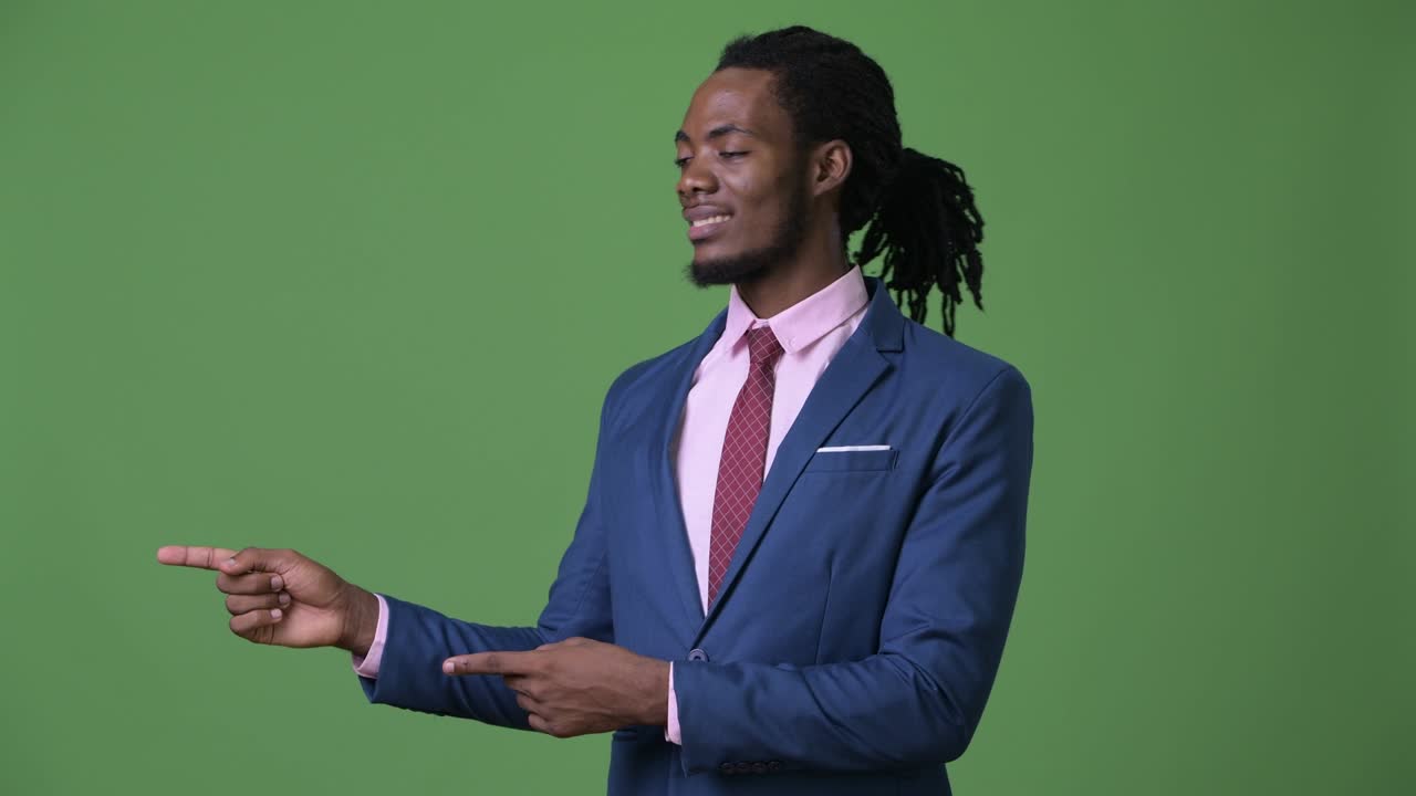 Young handsome African businessman with dreadlocks against green background