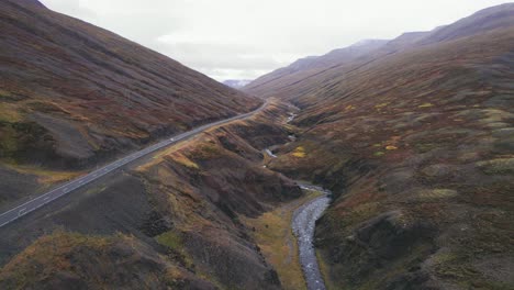 aerial: following white suv traveling along the iceland ring road which is a scenic highway through a picturesque remote fjord area leading to fog and haze in the distance