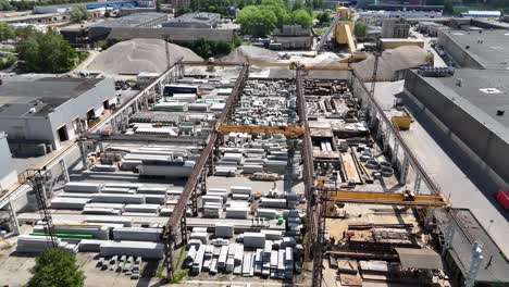 Industrieller-Betonhof-Mit-Kränen,-Die-Materialien-Unter-Sonnigem-Himmel-Bewegen