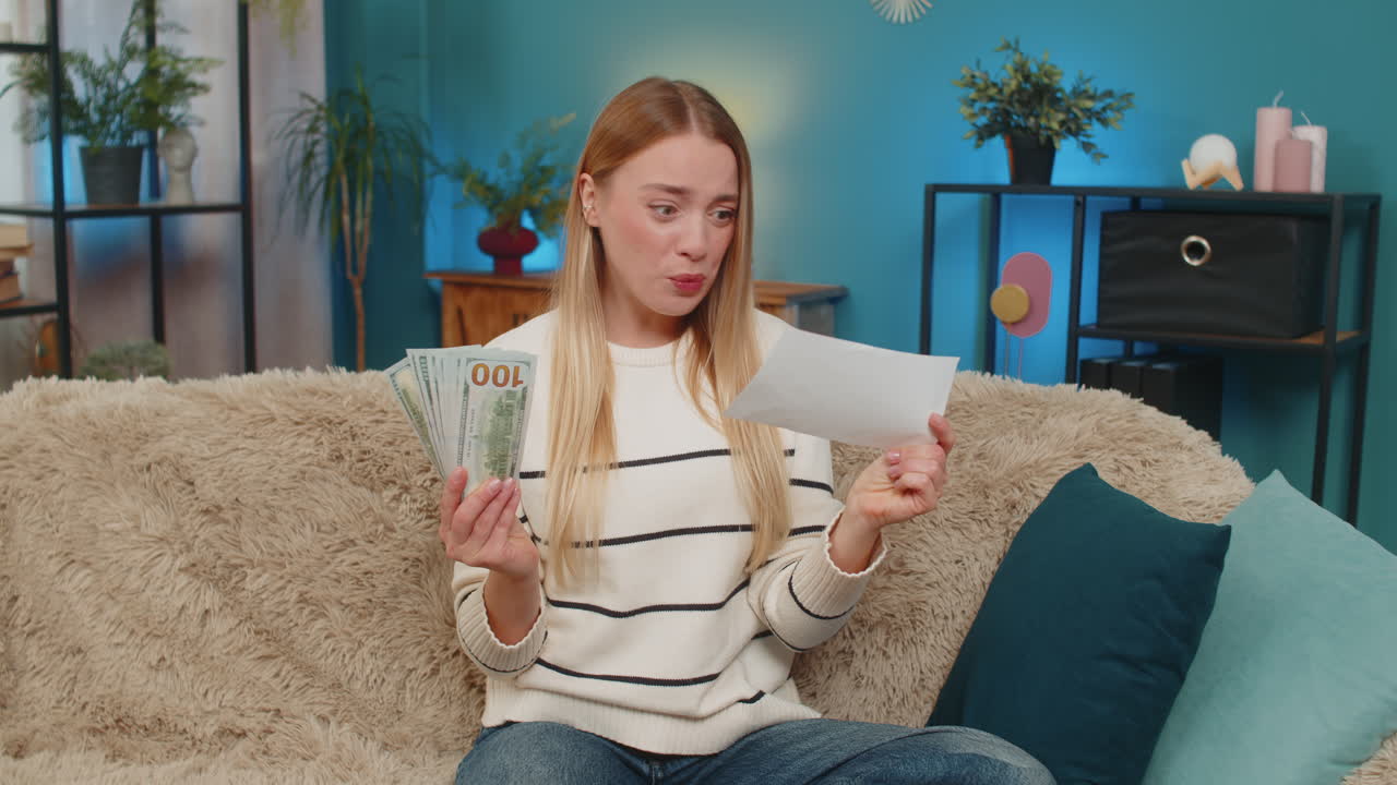 Caucasian woman winning lottery on sofa holding cash ticket jumping smiling looking camera indoors