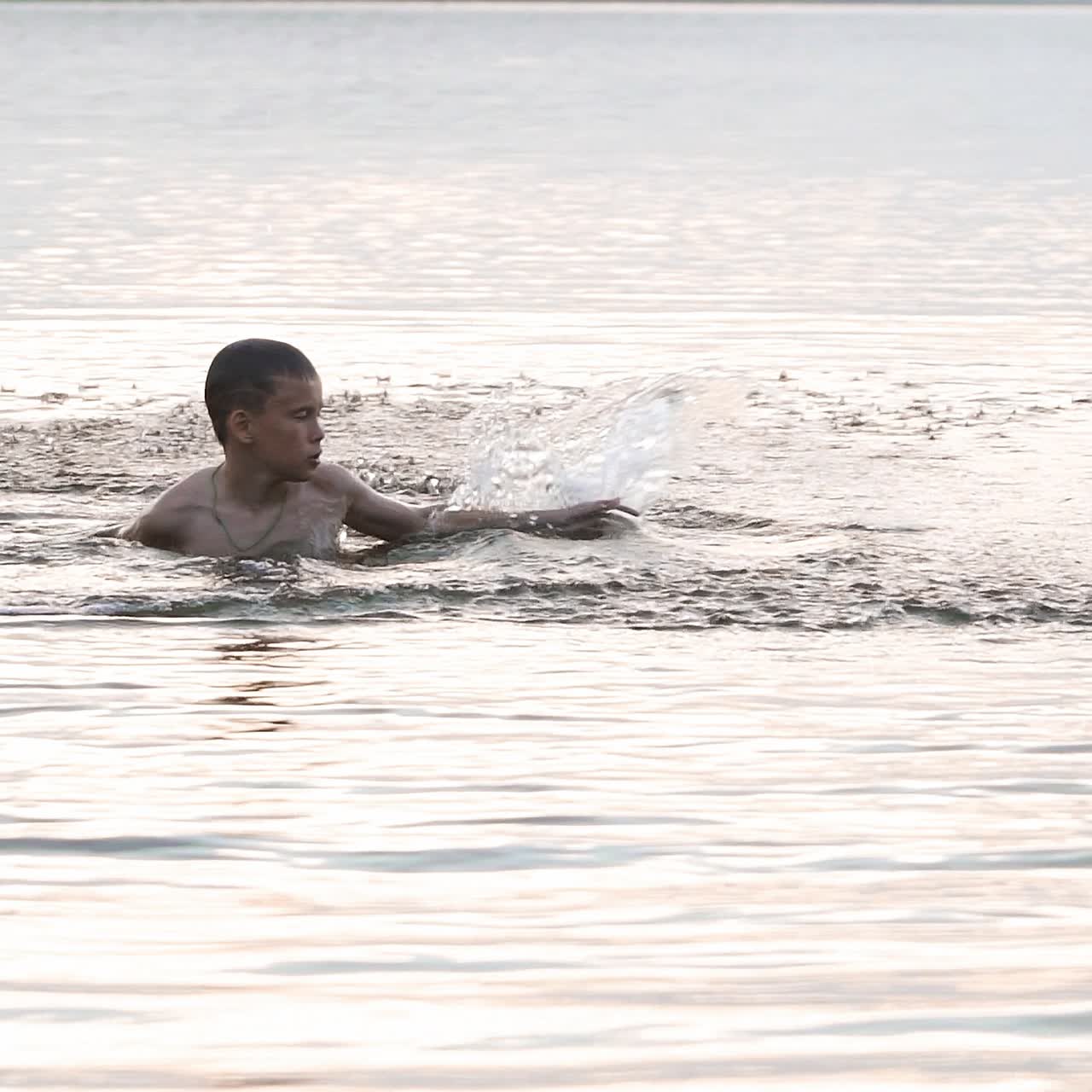 Slow motion of a child playing in the river. Happy boy having fun on vacation. Close-up shot of water splashes
