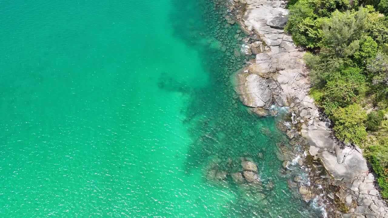 Aerial footage captures Phuket's vibrant turquoise waters and rocky shoreline, showcasing lush greenery and serene coastal beauty