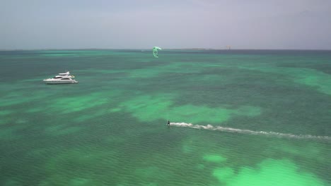 kite surfer rides over clear turquoise waters on a sunny day