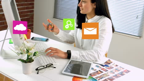 digital icons against woman playing with stress ball at office