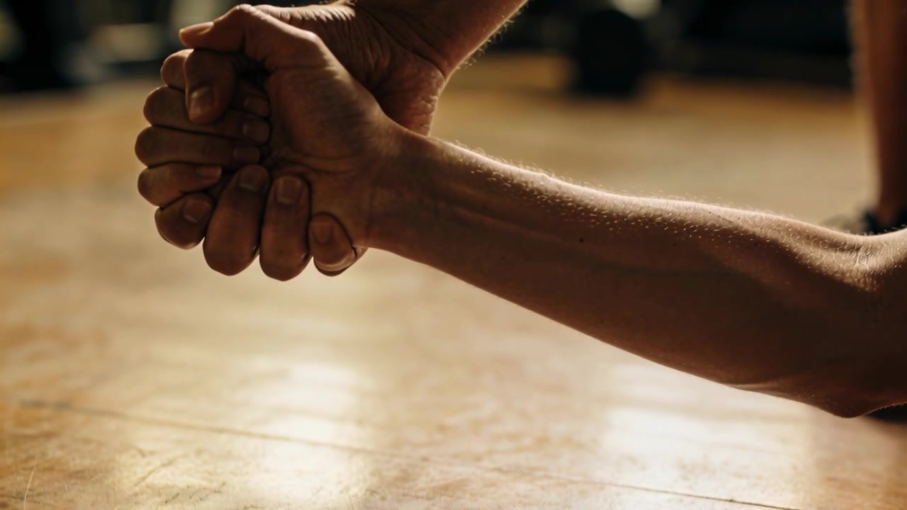 Reaching trainer pulling clasped hands on gym floor, assisting partner up with athletic shoe