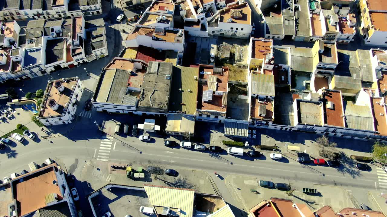 vista lineal de un avión no tripulado de una avenida en la ciudad de las cabezas de san juan, que muestra una plaza con un toldo colorido que proporciona sombra y todos los techos de las casas cercanas