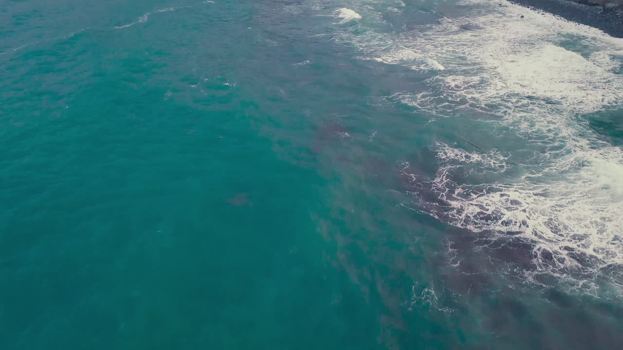 Aerial tilt up reveal of ocean coast and cliffs of Porto da Cruz, Madeira