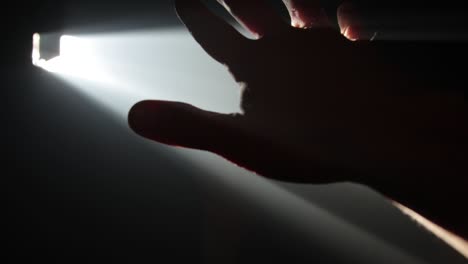 man holding his hand against ray of light