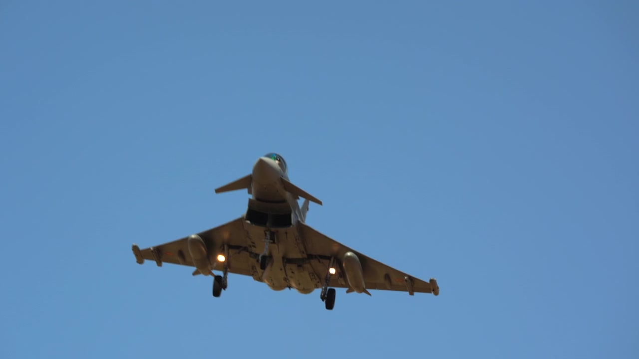 Fighter jet banking overhead in clear sky