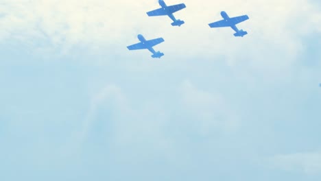 three red yak-50s aerobatic aircrafts carrying out dynamic maneuvers in front of spectators at baltic airshow in liepaja, latvia, handheld shot