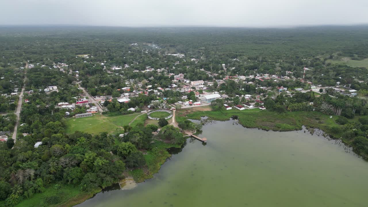 el avión gira sobre un pequeño pueblo en la laguna de noh bec en la selva mexicana.