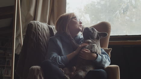 red haired woman caresses her bulldog dog while they are sitting on the sofa in the living room at home 2