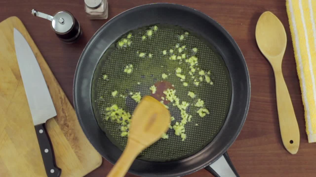 Aglio tritato che frigge in padella con olio d'oliva