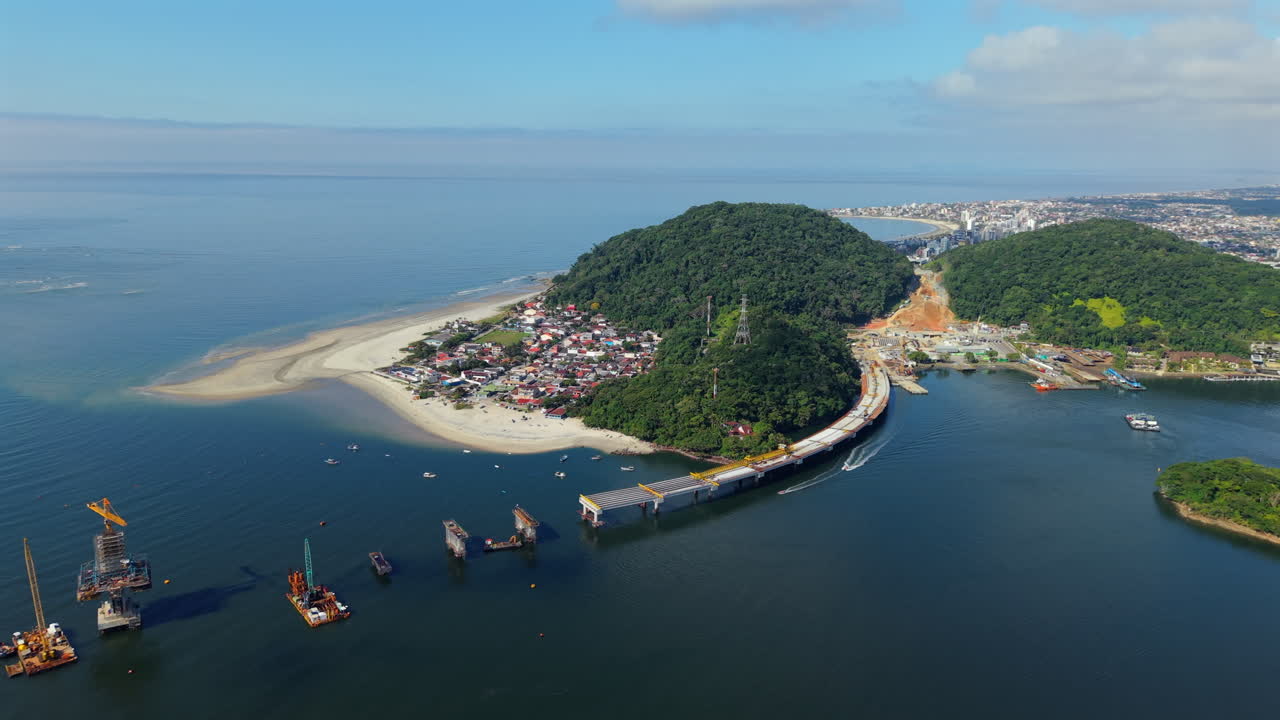 Drone slowly pulls out revealing the Ponte de Guaratuba bridge over Guaratuba Bay, connecting the cities of Matinhos and Guaratuba in Paraná, Brazil, with calm waters, forested hills, and boats