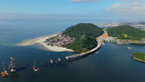drone slowly pulls out revealing the ponte de guaratuba bridge over guaratuba bay, connecting the cities of matinhos and guaratuba in paraná, brazil, with calm waters, forested hills, and boats