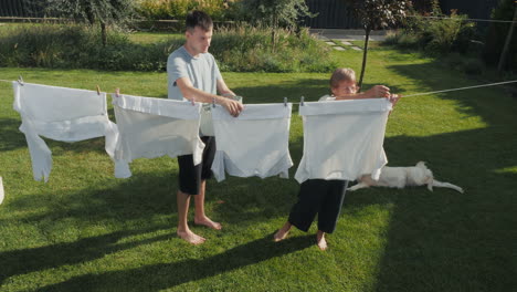hermanos secando la ropa en el patio trasero