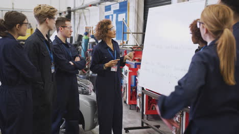 students studying auto mechanic apprenticeship at college asking female tutor questions