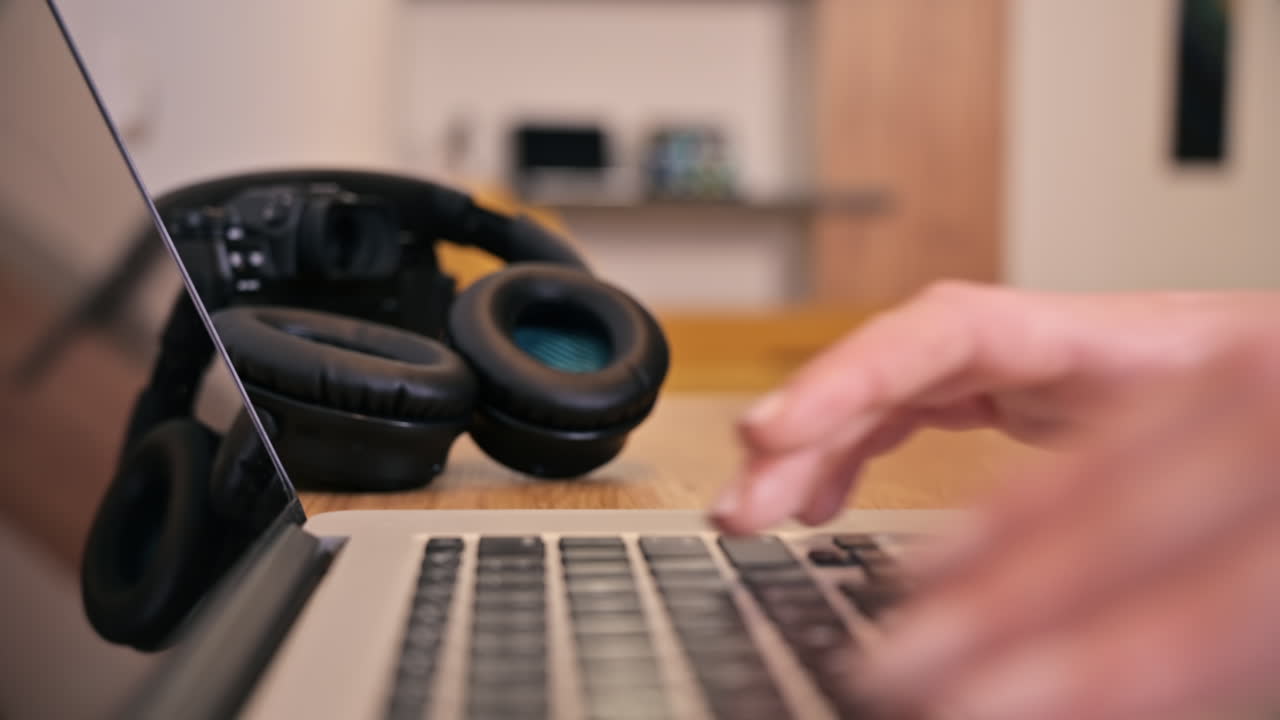 Female hands typing on laptop with headphones on background. Working from home