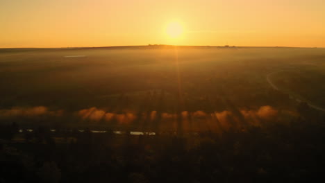 Toma-Aérea-De-Un-Increíble-Amanecer-Amarillo-Sobre-La-Niebla-Matutina-Y-Las-Nubes,-En-El-Campo-De-Moldavia