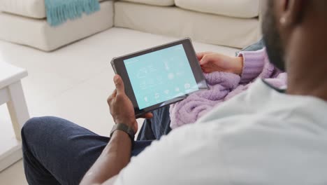 Diverse-couple-sitting-on-couch-and-using-tablet-in-living-room