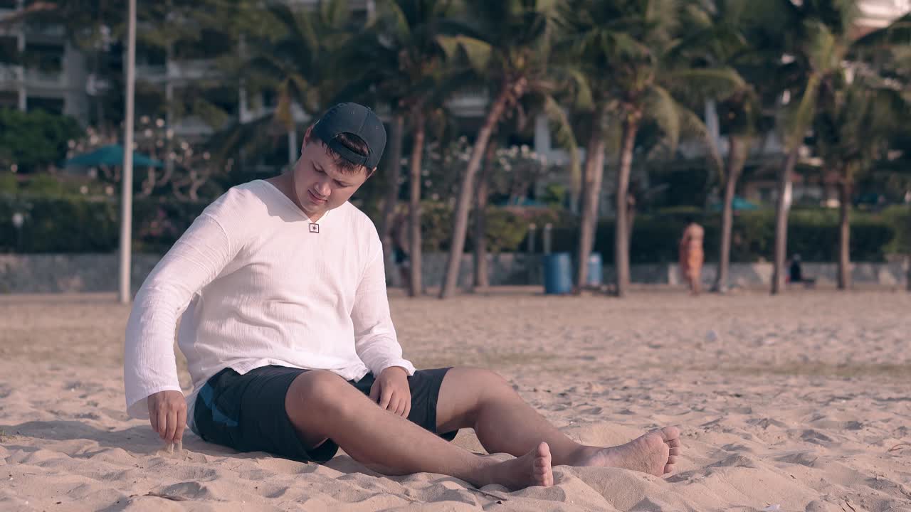 hombre descalzo juega con arena en la playa de la noche por el océano