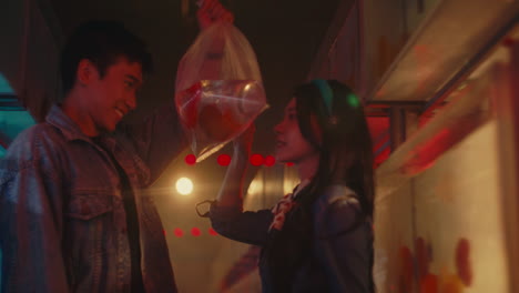 couple looking at fish in a bag at night market