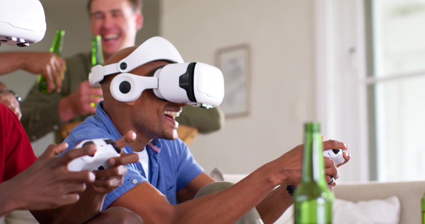 Amici maschi di diverse etnie che iniziano una partita a casa; un uomo con le cuffie si sporge e urla, tenendo il controller per competere.