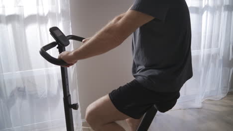 home training with stationary bicycle man is spinning pedals keeping fit during self-isolation in pandemic time physical activity at middle age