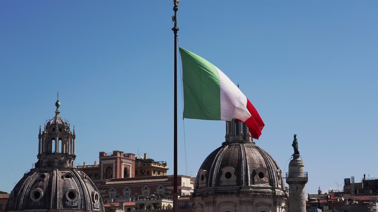 Inquadratura statica della bandiera italiana che sventola al vento con autentici edifici romani sullo sfondo a Roma, Italia in 4k