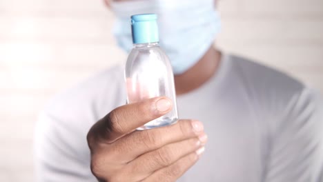 person holding hand sanitizer bottle with mask