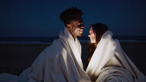 couple under a blanket on the beach at night