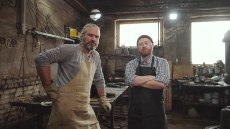 two blacksmiths posing for camera in workshop