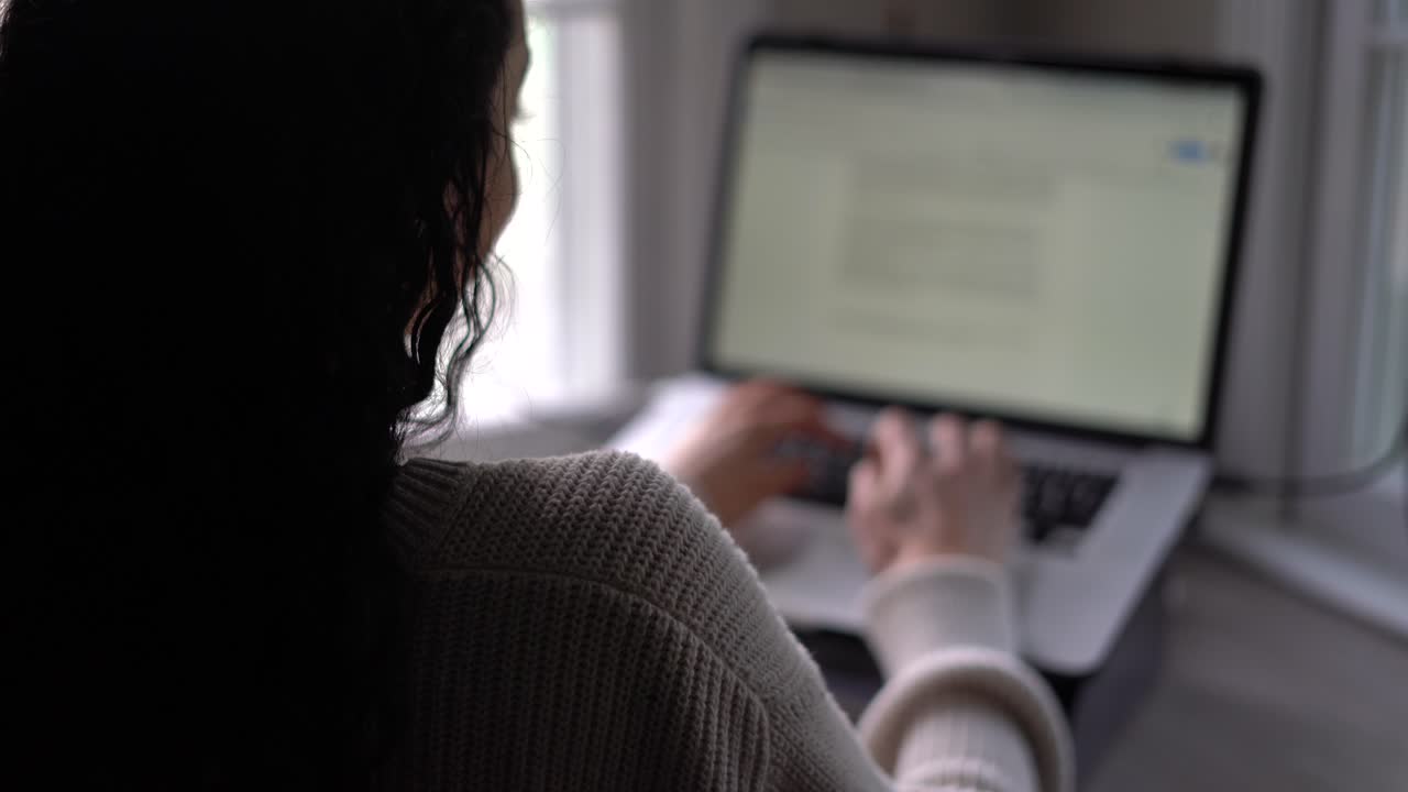 mujer joven escribiendo rápidamente en una computadora portátil o tableta con un teclado - vista desde atrás