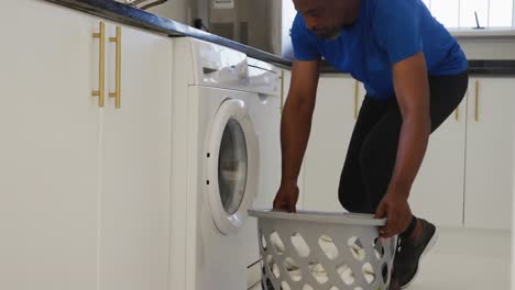 Afroamerikanischer-älterer-Mann,-Der-Zu-Hause-Schmutzige-Wäsche-In-Die-Waschmaschine-Steckt
