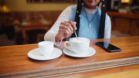 woman stirring cappuccino in a cafe