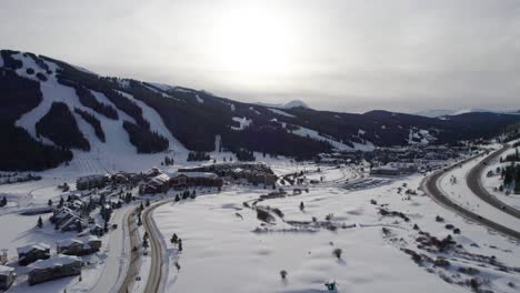 Drone-aerial-views-of-Copper-Mountain,-CO-with-the-sun-coming-through-clouds