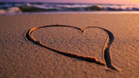 heart drawn in the sand at sunset