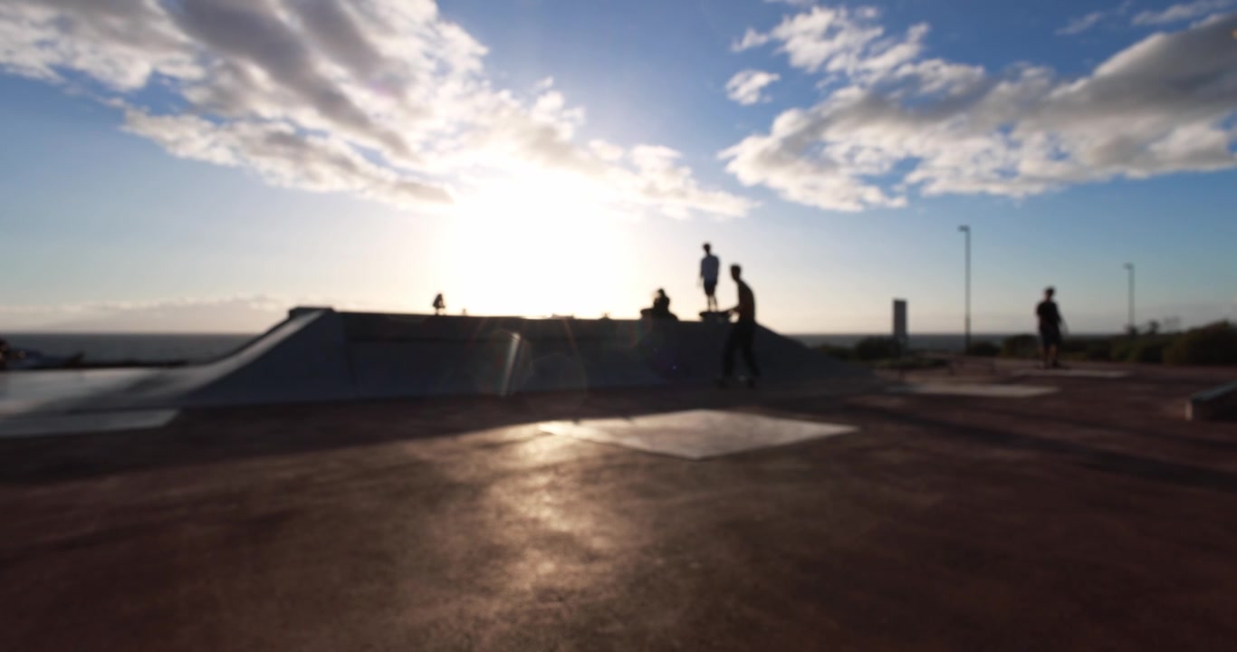 Sagome di skater e amici in uno skatepark al tramonto