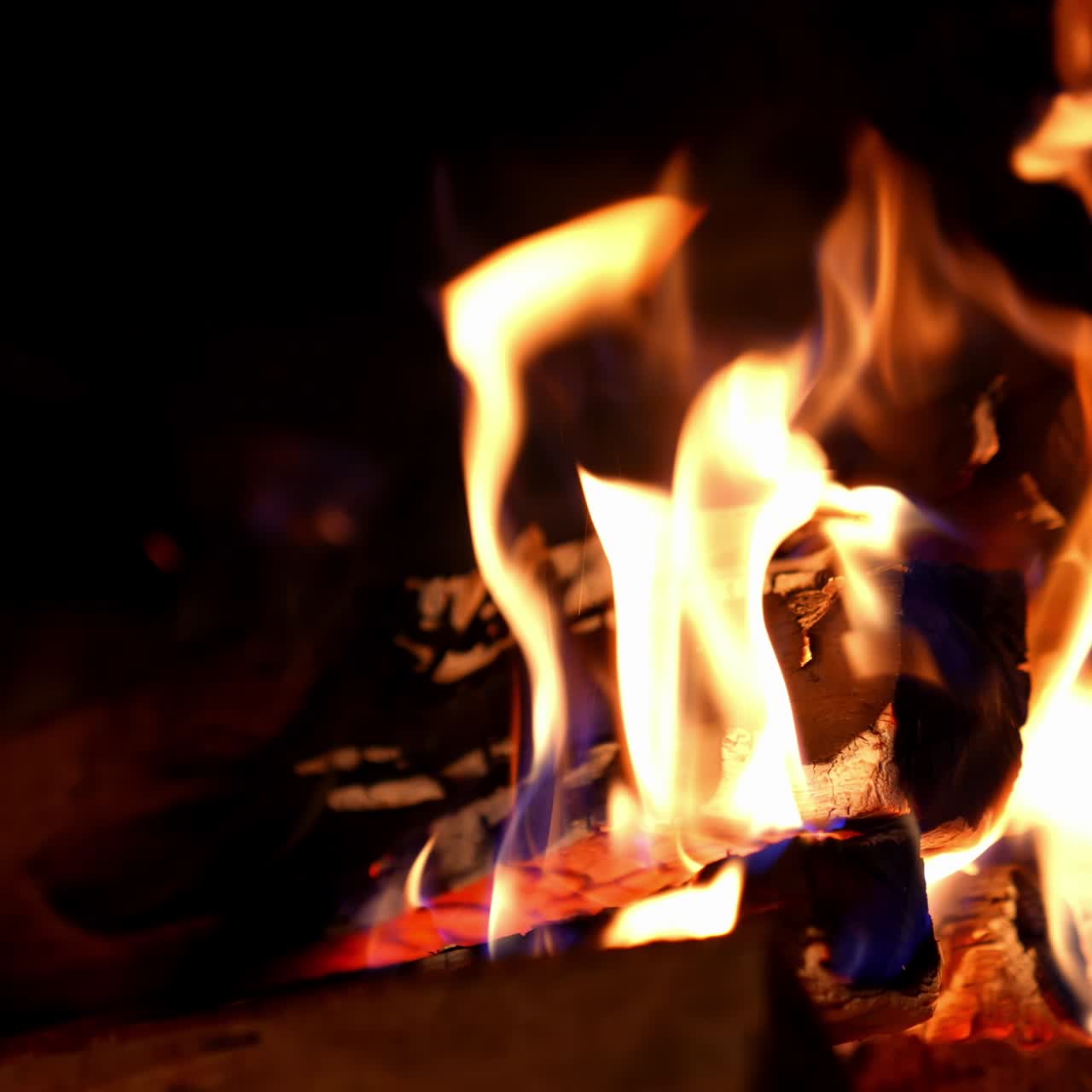 Cropped view of the wood burning in a fireplace during the night. Warm cozy fire in a fireplace. Autumn and winter holidays. Home cosiness concept