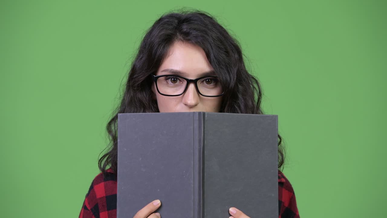 Young beautiful businesswoman covering face with book