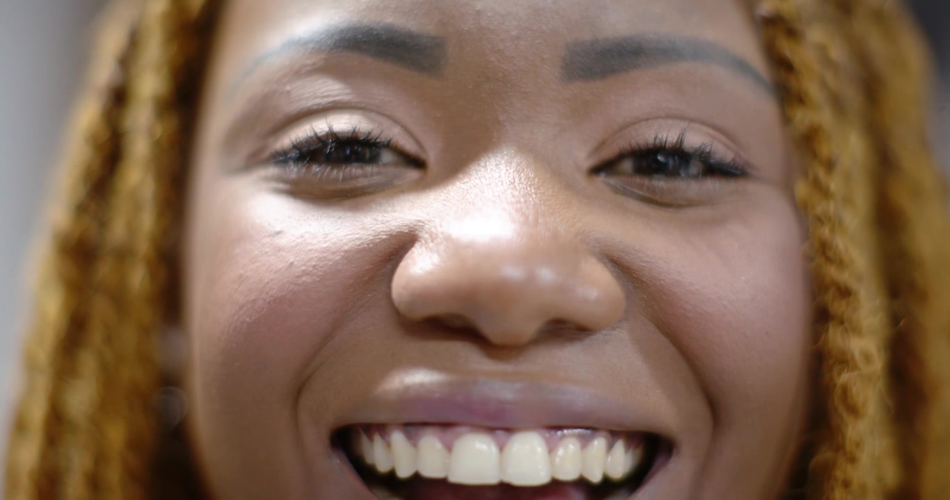 African mid-adult female reacting to camera, smiling and widening, showing braided hair in studio
