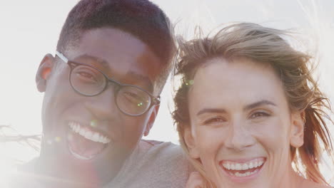 head and shoulders portrait of smiling young friends outdoors together against flaring sun