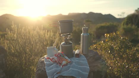 dolly shot reveals saucepan on portable stove placed on rock at bright campsite in england, uk