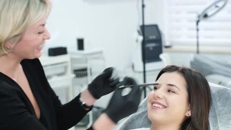 eyebrow specialist measuring and shaping client's eyebrows for microblading
