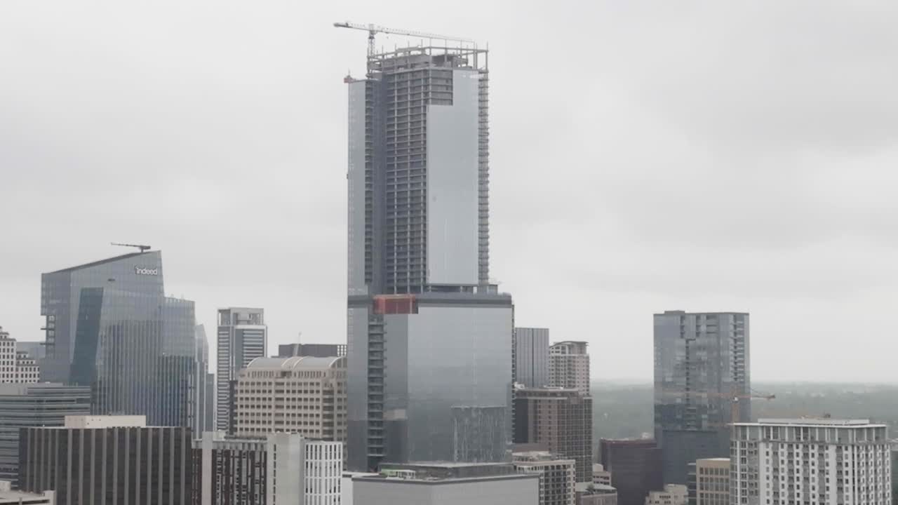 vista de paralaje de avión no tripulado de cerca de un edificio en el centro de austin, texas con inclinación hacia el vecindario
