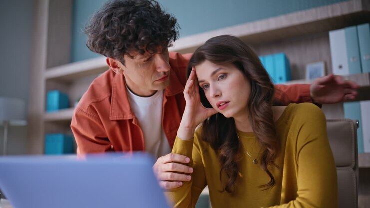 Primi piani di colleghi stressati che guardano un laptop, delusi da una brutta notizia. Uomo e donna colpiti da una perdita