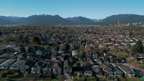 Toma-Aérea-Sobre-El-Barrio-De-La-Ciudad-De-Vancouver,-Temporada-De-Flores-De-Cerezo-En-Dunring,-Con-Las-Montañas-Al-Fondo-En-Un-Día-Soleado,-área-Suburbana-De-Burnaby,-Columbia-Británica,-Canadá