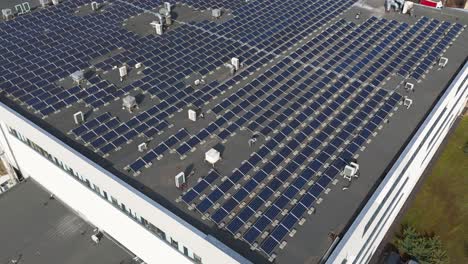 Aerial-shot-of-the-solar-panels-on-a-production-building-roof-on-a-sunny-day-in-Kaunas,-Lithuania