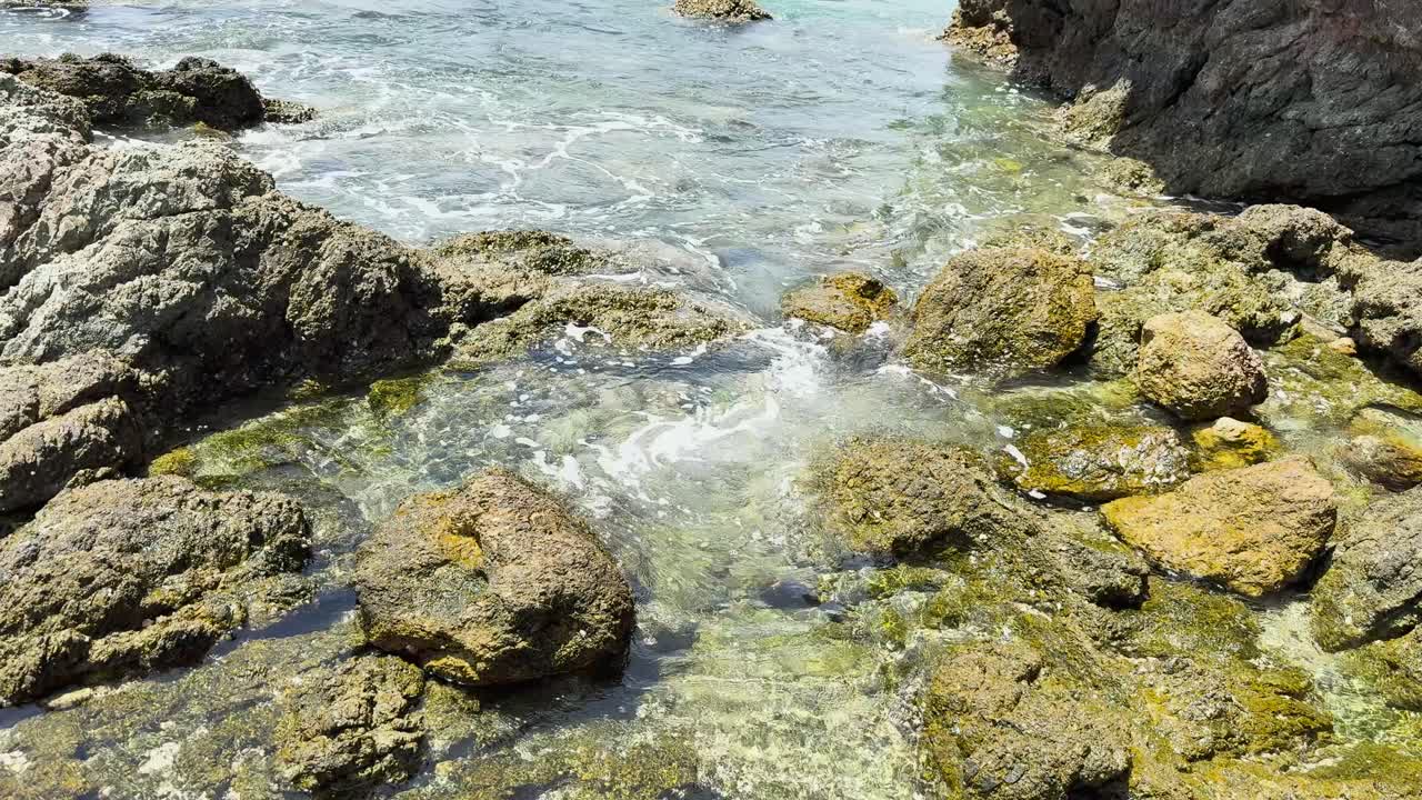 las olas se lavan suavemente sobre las rocas en una piscina de marea serena en la playa de yanui, phuket, capturada a la luz del día