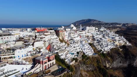 Oia-village-cliffside-houses-and-hotels-in-Santorini,-Greece,-Cinematic-aerial-view